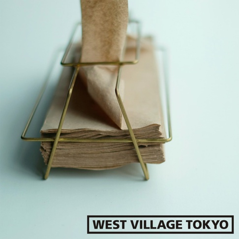 黃銅金屬質感的收納面紙盒，盛裝著一疊淺棕色面紙，盒身線條簡約，呈現金屬光澤。