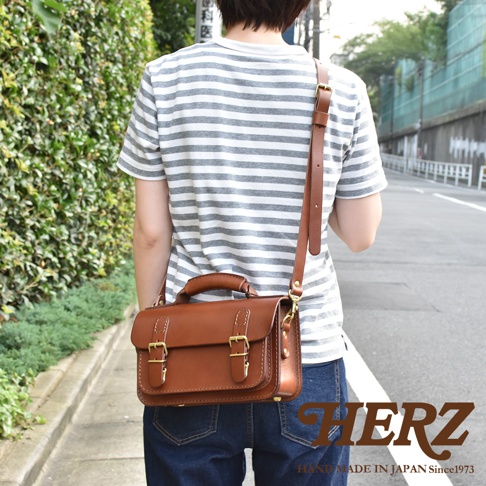 職人手作皮革雙扣兩用迷你肩背包，經典棕色，採用高品質皮革製作，配有可調節肩帶和兩個金色搭扣，設計簡潔實用。