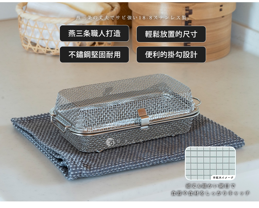 不鏽鋼製長方形網狀收納盒，帶有金屬鎖扣，放置於灰色紋理的布料上。