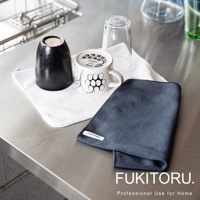 兩條超極細纖維擦拭布，一條為白色，一條為深藍色，表面有細緻的織紋。圖片中還有一黑一白兩個杯子，以及兩個玻璃杯，皆放置在金屬檯面上。