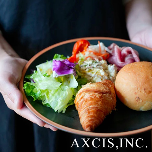 黑色陶瓷主菜盤裝有沙拉、可頌、麵包、火腿片和馬鈴薯沙拉，盤緣有淺棕色邊飾。