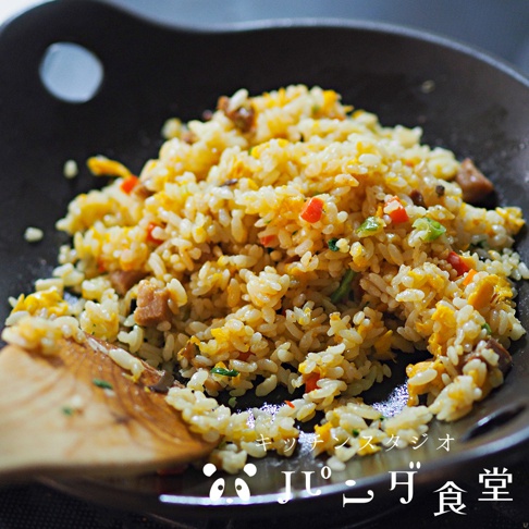 Kitchen Studio Panda食堂的炒飯，盛裝在一個黑色料理盤中，炒飯中含有米飯、雞蛋、肉塊和蔬菜丁。