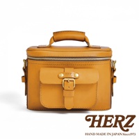 日本 HERZ 品牌復古棕色皮革相機包，配有金色搭扣的正面翻蓋口袋和頂部提把。