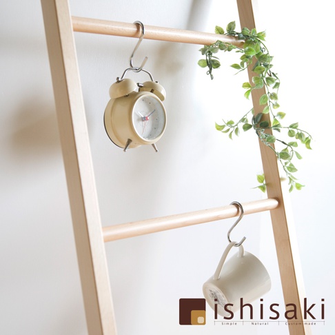 木製牆面收納架，淺木色，帶有兩層橫桿。一個淺黃色復古鬧鐘掛在上方橫桿，一白色馬克杯掛在下方橫桿。右側橫桿上裝飾著綠色藤蔓。