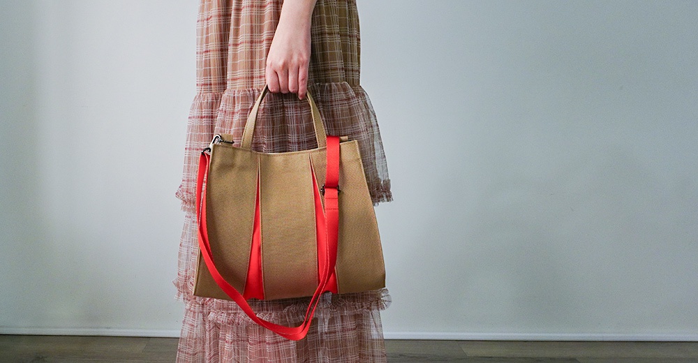 京都職人手作ougi棉帆布兩用扇形托特包，主體為卡其色帆布材質，配有鮮豔的紅色織帶提把與肩帶，包身呈現扇形輪廓，設計簡約俐落。