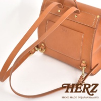 棕色皮革迷你後背包，翻蓋設計，附可調式肩帶和金色金屬扣環。包身有精緻的縫線細節，並印有品牌標誌。