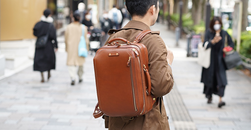 職人手作棕色皮革兩用商務後背包，設有拉鍊隔層、頂部提把及可調式肩帶，適合商務和日常使用。