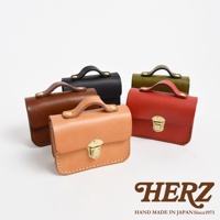 職人手作皮革迷你收納包，展示多種顏色（包括棕色、黑色、紅色、綠色和橘色），採用真皮材質，配有金色金屬扣環和提把，風格簡約。