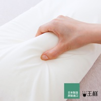 一隻手正在擠壓一個白色天竺棉材質的枕套，展現其柔軟度和彈性。