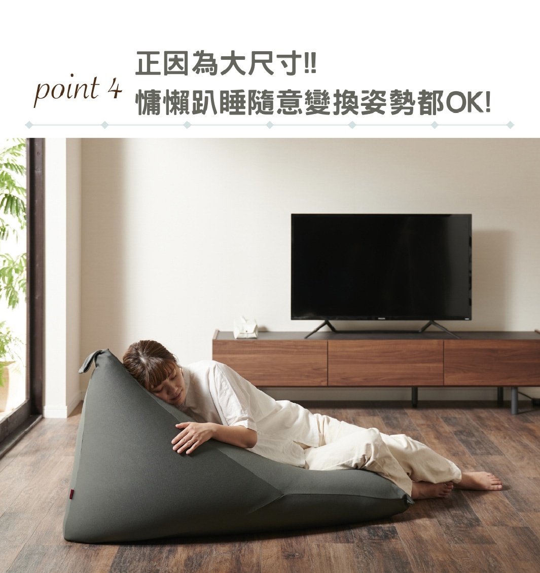 針織布款懶骨頭沙發，深灰色，一人斜躺於上，背景為居家客廳場景，包含電視櫃及電視。