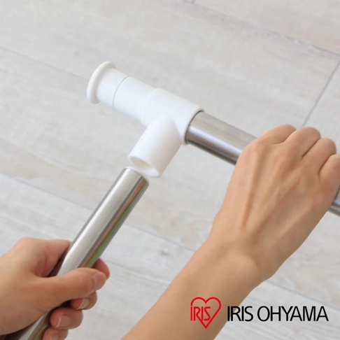 兩隻手正在組裝不鏽鋼曬衣架，白色塑膠接頭連接銀色不鏽鋼管。