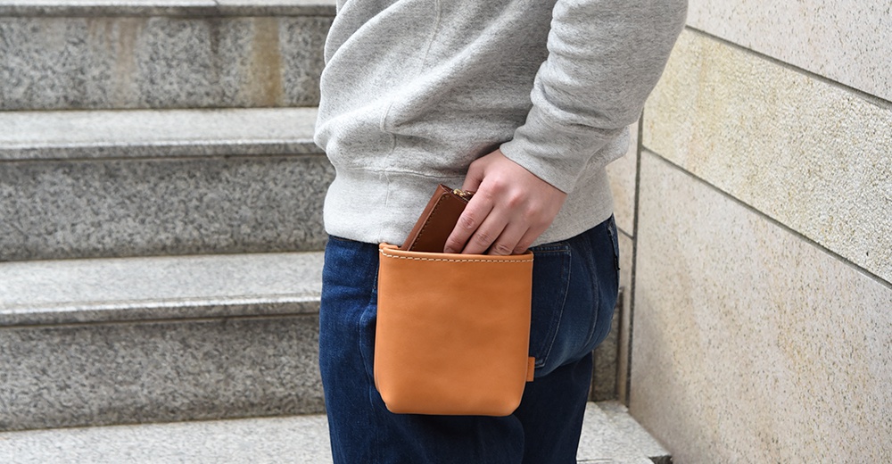 淺棕色皮革製作的腰袋，附有白色縫線，腰袋內裝有一支深棕色皮夾。