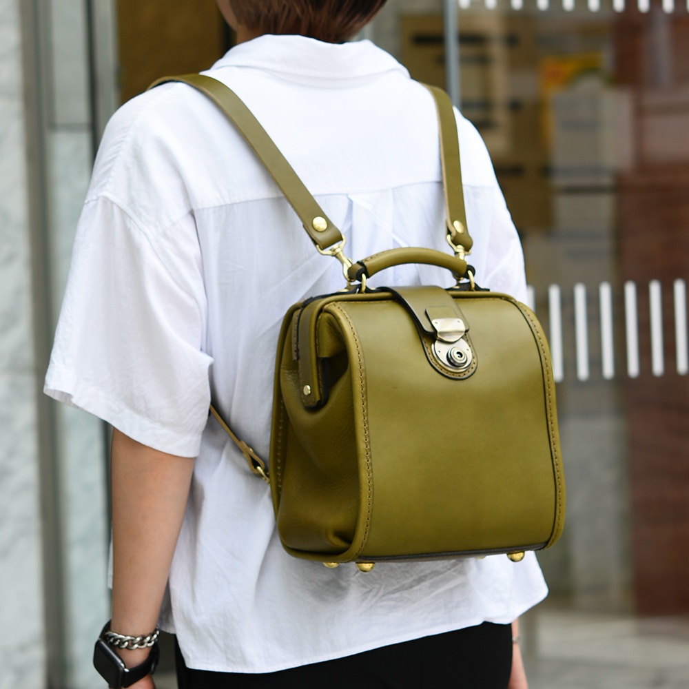 橄欖綠皮革迷你後背醫生包，附有金色金屬旋鎖和提把，皮革材質，背帶可調節，適合日常使用。