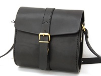 黑色皮革單肩包，配有金色皮扣和可調節肩帶。包身線條簡潔，縫線清晰，展現職人手作質感。