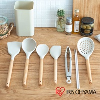 一套七件式廚房用具，包含白色矽膠鍋鏟、湯勺、漏勺、夾子和一雙筷子，皆配有木質手柄，擺放在木質檯面上。