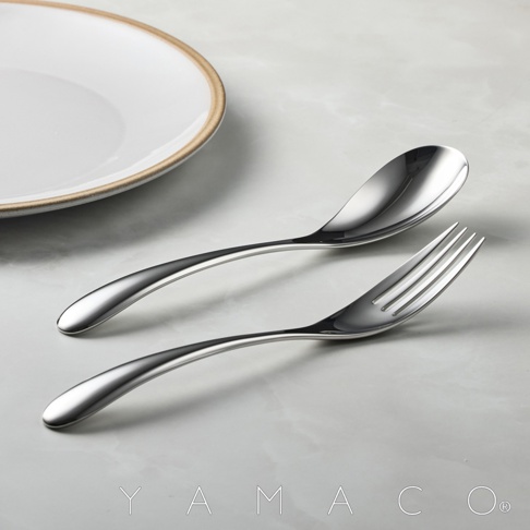 一個不鏽鋼湯匙和叉子，以及部分白色盤子，背景為淺灰色。