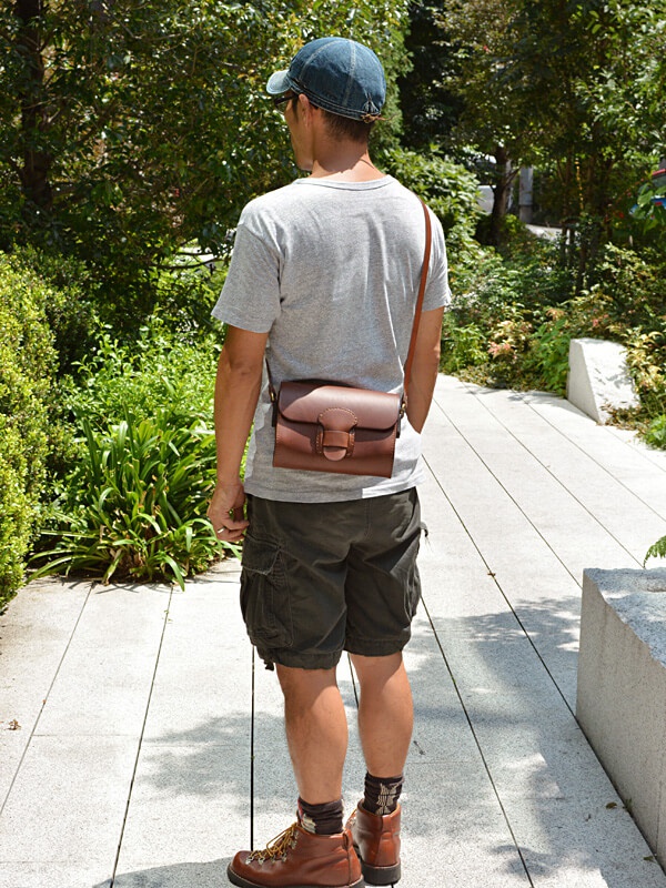 職人手作皮革寬扣帶馬鞍包，採用深棕色皮革製成，帶有寬版金屬扣帶，可斜肩配戴，展現簡約復古風格。