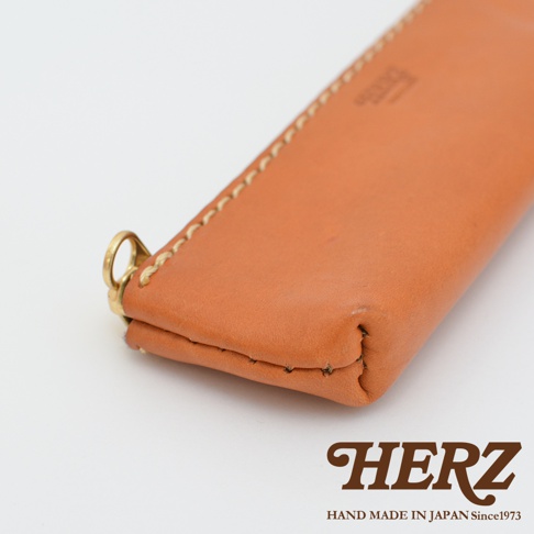 職人手作皮革經典收納筆袋 KP-25，採用天然皮革材質，呈現溫潤的棕褐色，配有金屬環扣，側邊以米白色縫線手工縫製。