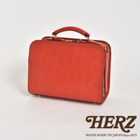 職人手作皮革兩用方形單肩包，採用亮橘色皮革製成，帶有提把，側邊有拉鍊開合，風格簡約。