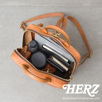 職人手作皮革Organ商務後背包，打開內部陳列著筆記本、文件夾、折疊傘、圓形收納盒及皮夾等物品，展現實用收納空間。