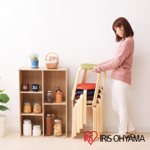 木質圓椅凳堆疊，椅凳上有綠色、紅色、藍色、棕色和米色椅墊。