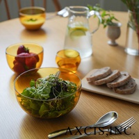 琥珀色玻璃點心碗，一個裝滿新鮮草莓，另一個盛著綠葉沙拉。背景有裝水的玻璃水瓶、切片的麵包和一碗湯。