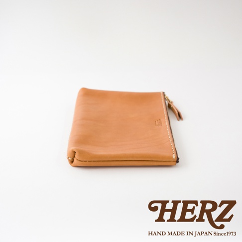 職人手作皮革長方形拉鍊收納包，淺棕色皮革，附有黃銅色拉鍊及皮革拉袢，車縫線清晰可見，整體風格簡約。