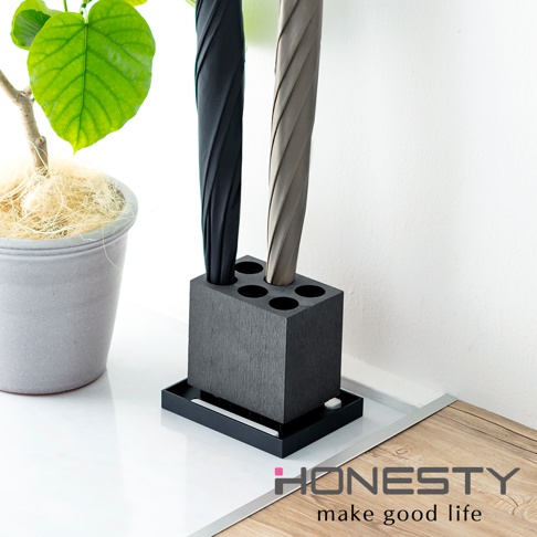 黑色珪藻土可拆式六孔傘架，簡約方形設計，搭配灰色與黑色摺疊傘，旁邊有一個灰色盆栽，整體呈現現代居家風格。