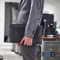 黑色皮革材質的行動折疊腰靠坐墊D，表面有細緻的透氣孔設計，由穿著灰色西裝的人士手持。