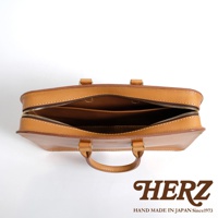 職人手作淺棕色皮革公事包，頂部視角，拉鍊開啟，露出內部隔層，附有兩個提把。