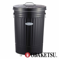 OBAKETSU 手工製附輪垃圾桶，黑色金屬材質，帶有提把的圓頂蓋，上面印有 OBAKETSU 商標。