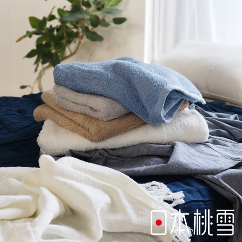 堆疊的飯店方巾，顏色包含淺藍、淺灰、卡其、白色和深灰，材質為柔軟的毛巾布。