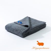 深灰色竹棉混紡厚實大浴巾，表面有柔軟絨毛，一角縫有藍色標籤，印有橘色河馬圖案。