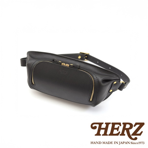 HERZ 職人手作皮革拉鍊旅行斜背包 F-7，黑色Stare皮革材質，設有兩個拉鍊夾層，搭配金色拉鍊，斜背帶可調整長度，背面壓印品牌標誌，整體呈現簡約俐落的風格。