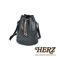 黑色職人手作皮革束口單肩包，圓筒狀包身，頂部有束繩設計，附有可調式單肩背帶，整體為簡約風格。