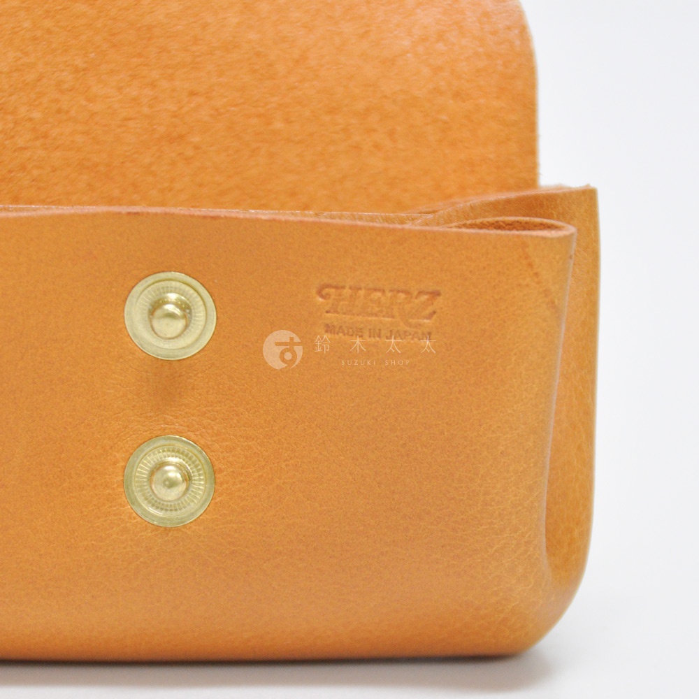 職人手作皮革三層收納零錢包，展現天然皮革的紋理與溫潤質感，採用經典卡其色，搭配兩個金色按扣，正面烙印著「HERZ」品牌標誌。