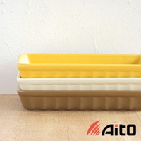 堆疊擺放的美濃燒釉彩萬用長方烤盤，從上至下顏色分別為亮黃色、米白色與淺褐色。烤盤為陶瓷材質，側邊有立體溝紋裝飾，造型簡潔實用。