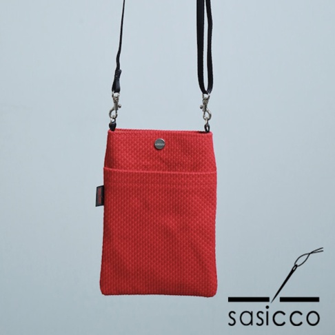 紅色三河木綿刺子織手機包，正面有一個較淺的口袋，上方有金屬釦，搭配黑色細背帶。