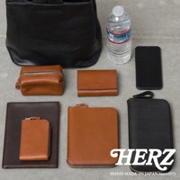 黑色皮革托特包、棕色皮革化妝包、棕色皮革短夾、黑色皮革長夾，以及一個棕色皮革卡夾，手機和一瓶水。