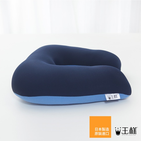 深藍色U型枕，外層柔軟布料，內裡填充物飽滿，底部有淺藍色滾邊，右側有品牌標籤。