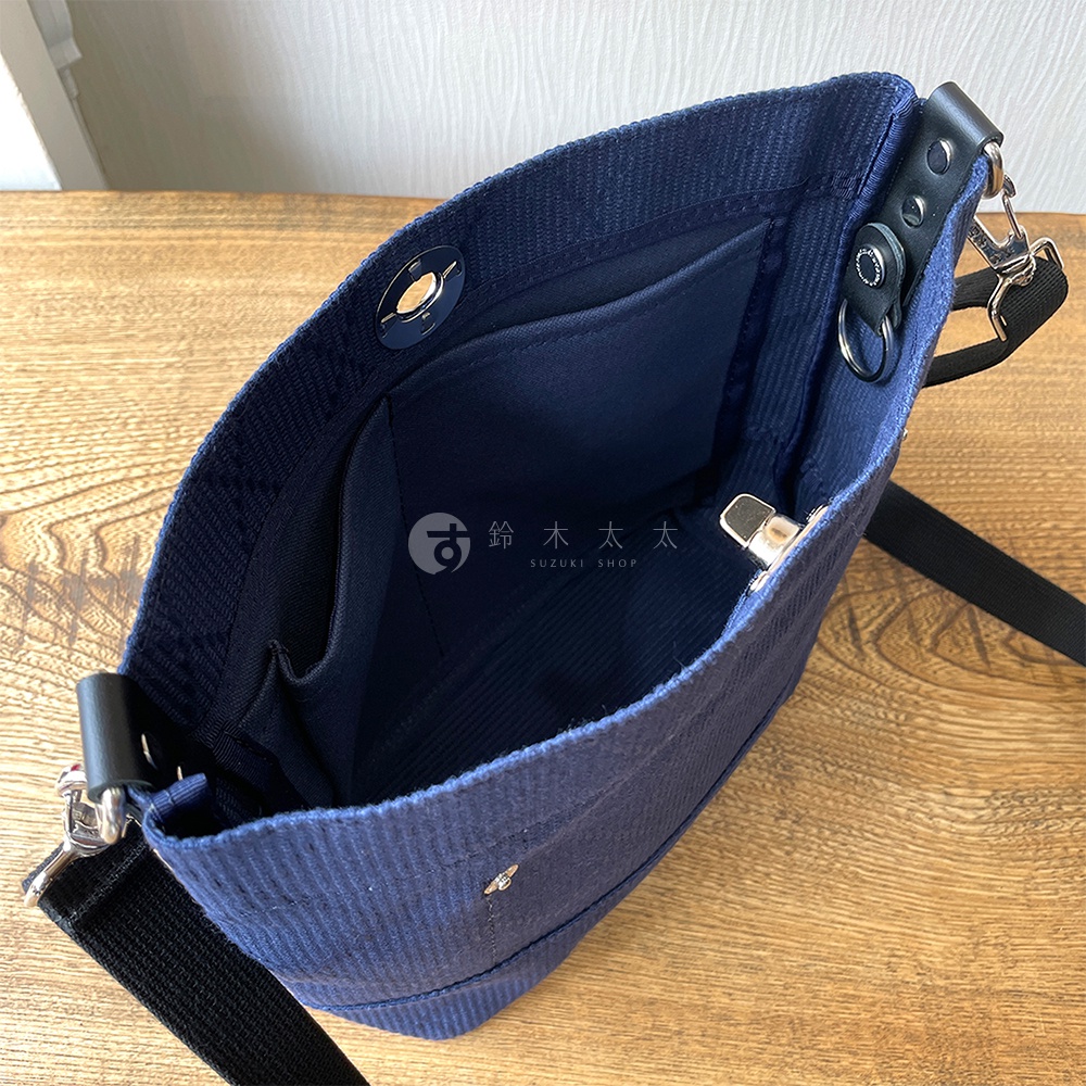 深藍色燈芯絨迷你側背包，內部有隔層和口袋，配有黑色織帶和銀色金屬配件。