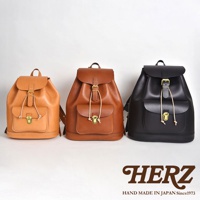 三款職人手作皮革經典後背包，分別為淺棕色、棕色和黑色。皆為抽繩束口設計，附有翻蓋及金屬扣環，正面有一個小口袋，同樣為翻蓋與束繩設計，展現經典實用風格。