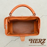 職人手作皮革Organ方形口金托特包，呈現自然棕色，材質為厚實皮革，包身結構方正，頂部設有提把及金屬口金開合，內部空間寬敞，可見皮革隔層與縫線細節。