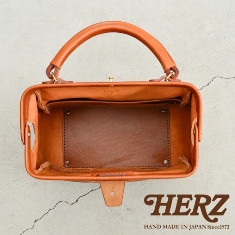 職人手作皮革Organ方形口金托特包，呈現自然棕色，材質為厚實皮革，包身結構方正，頂部設有提把及金屬口金開合，內部空間寬敞，可見皮革隔層與縫線細節。