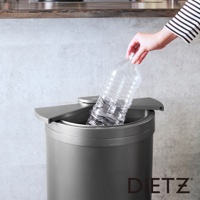 一個灰色的30公升大容量自動感應靜音垃圾桶，桶身呈圓柱形，配有銀灰色觸控蓋，一位女士正將一個裝有液體的透明塑膠瓶投入桶中。