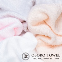 柔軟的毛巾堆疊，呈現粉色、白色和淡橘色。毛巾材質蓬鬆，紋理清晰可見。