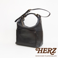 黑色厚實皮革製成的單肩波士頓包，包身有拉鍊開口，正面有兩個開放式口袋，口袋上方有品牌標誌，肩帶可調整，整體風格簡約。