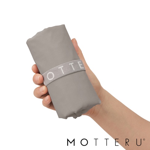 手持灰色輕時尚摺疊保冷可拆托特袋，袋身以灰色布料製成，並以灰色彈性束帶固定，束帶上印有白色「MOTTE」字樣。