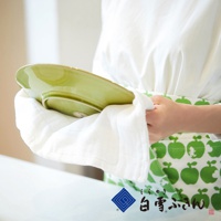 白色木纖維拭巾，質地柔軟，正擦拭著一個淺綠色的盤子，盤子上有一圈淺色邊緣。