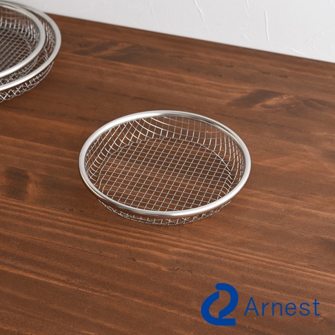 一個圓形金屬網狀濾網，有銀色邊框，放置在木質桌面。